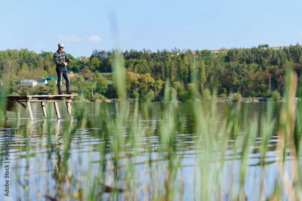 Obraz premium A man catches a fish on a spinning fishing in the summer