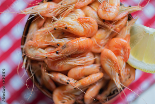 Black sea shrimps. Fresh cooked sea shrimps in a bowl on a on the background of a red & white tablecloth. Seafoood. Sea products macro. Beer snack.  photo