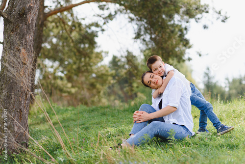 Happy family! Mother with son child playing having fun together on the grass in sunny summer day, life moment © Serhii