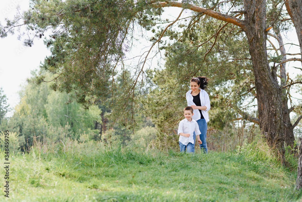 Happy young mother is playing with her baby in a park on a green lawn. Happiness and harmony of family life. Great family vacation. Good weekend. Mothers Day. Holiday. The concept of a happy family