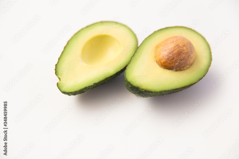 Halved avocado fruit with core. Closeup shot. Isolated object on white background. Fresh food or healthy diet concept