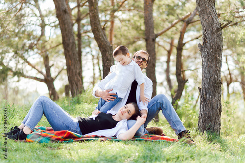 happy young family spending time outdoor on a summer day have fun at beautiful park in nature while sitting on the green grass. Happy family.