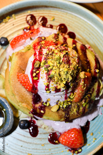 Matcha powder pancakes served in a restaurant setting, with ice cream, strawbberries and chocolate photo