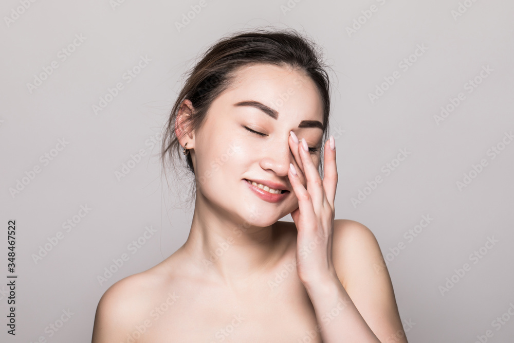 Asian woman beauty face closeup portrait. Beautiful attractive mixed race Asian female model with perfect skin isolated on gray background Asian woman beauty face closeup portrait. Beautiful attractive mixed race Asian female model with perfect skin isolated on gray background