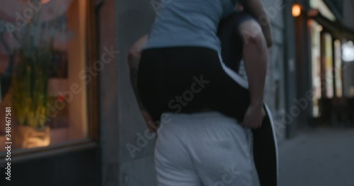 A young woman jumping up on boyfriend's back in the city.