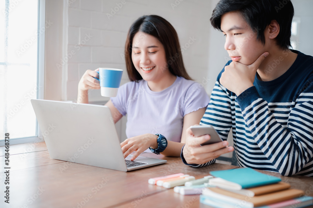 Young asian couple discussing together and typing on computer during working day in home office. Working from home concept Young asian couple discussing together and typing on computer during working day in home office. Working from home concept