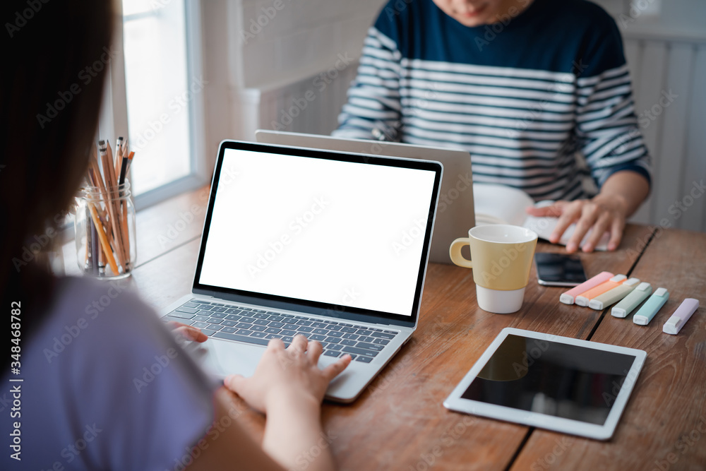 Two young employees in casual wear typing on mockup white screen computer during working day in home office. Working from home concept Two young employees in casual wear typing on mockup white screen computer during working day in home office. Working from home concept