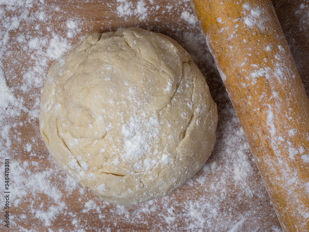 Raw dough covered with flour on a wooden cutting board. Raw dough covered with flour on a wooden cutting board.
