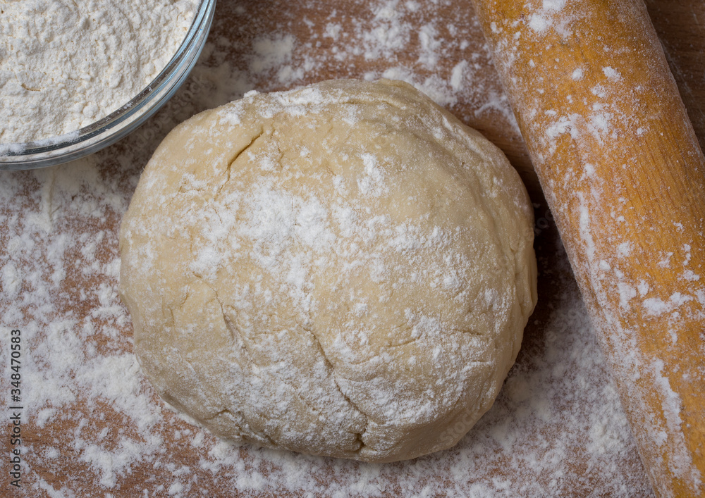 Raw dough covered with flour on a wooden cutting board. Raw dough covered with flour on a wooden cutting board.