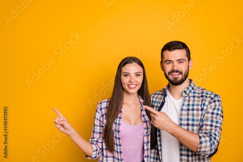 Portrait of positive cheerful team promoter woman man point index finger copyspace indicate ads promo direct way wear checkered plaid shirt isolated over bright shine color background