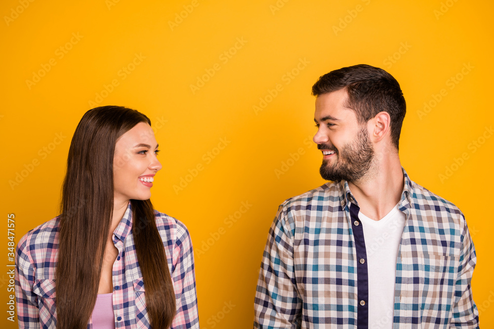 Closeup photo pretty lady handsome guy couple stand keep distance smiling look eyes talk without touch contacting laughing wear casual plaid shirts isolated yellow color background Closeup photo pretty lady handsome guy couple stand keep distance smiling look eyes talk without touch contacting laughing wear casual plaid shirts isolated yellow color background