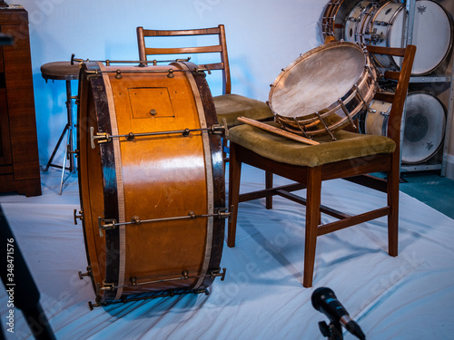 Very early drum kit from 1900s with snare drum placed on a chair. Pair of drumsticks on chair