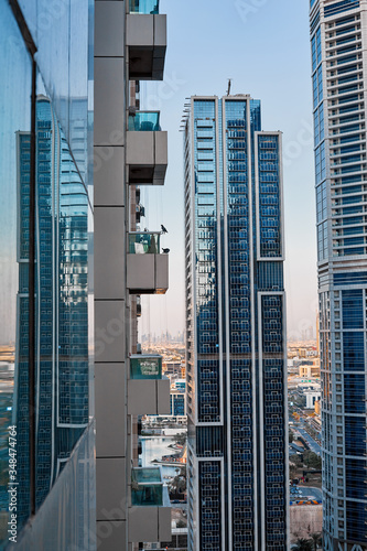 Modern architecture of a skyscraper with a large number of balconies against the background of the blue sky and the city
