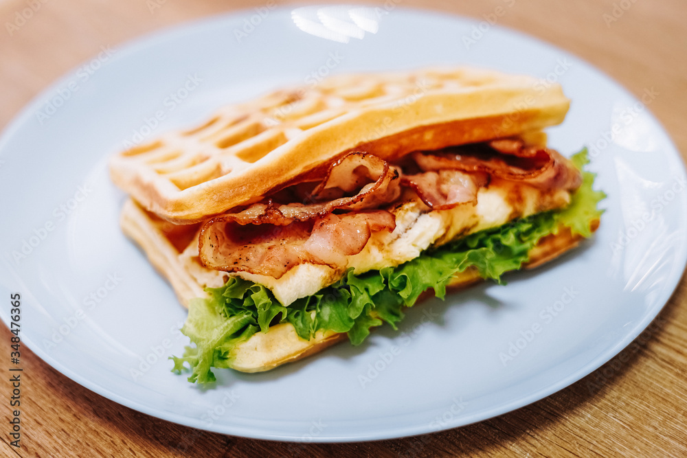 tasty Belgium waffle with lettuce, meat, egg and vegetables served of pretty blue plate tasty Belgium waffle with lettuce, meat, egg and vegetables served of pretty blue plate