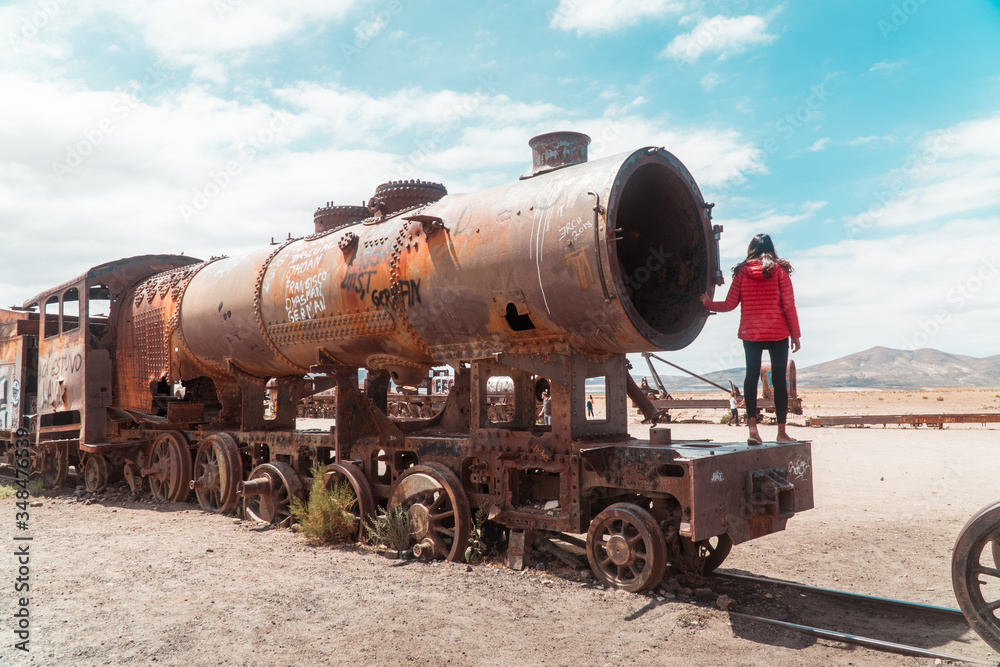 Tourist, Train Cemetry Bolivia Salt Flats. Bolivian salty desert and blue sky background. Shot in Salar de Uyuni. Rusted, waste, abandoned, locomotive graveyard, railroad concepts. Tourist attraction