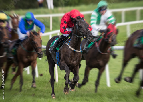Motion blur speed effect on race horses and jockeys galloping on the race track
