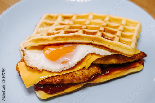 tasty Belgium waffle with lettuce, meat, egg and vegetables served of pretty blue plate