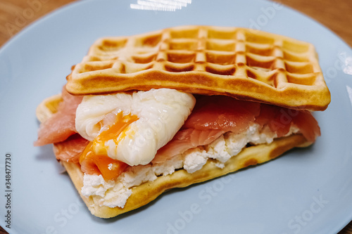 tasty Belgium waffle with lettuce, meat, egg and vegetables served of pretty blue plate