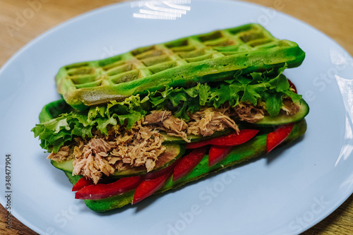 tasty Belgium waffle with lettuce, meat, egg and vegetables served of pretty blue plate