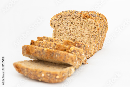 Cut rye loaf baked at home. Sliced delicious cereal pieces laying together isolated on white background. Studio shot. Selective focus. Side view. Homemade bakery and nutrition concept