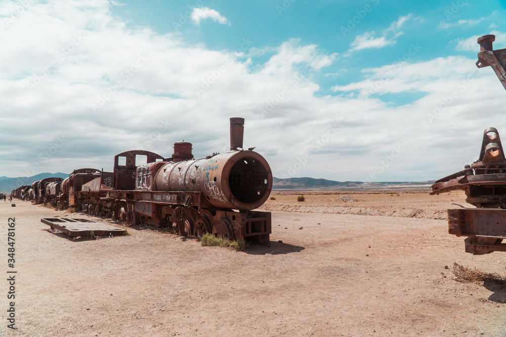 Train Cemetry Bolivia Salt Flats. Bolivian salty desert and blue sky background. Shot in Salar de Uyuni. Rusted, waste, abandoned, locomotive graveyard, railroad concepts. Tourist attraction