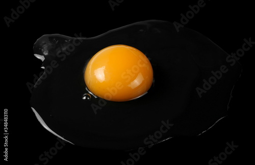 Raw egg white and yolk isolated on black background