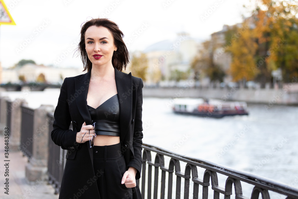 Woman in black pantsuit walks on promenade
