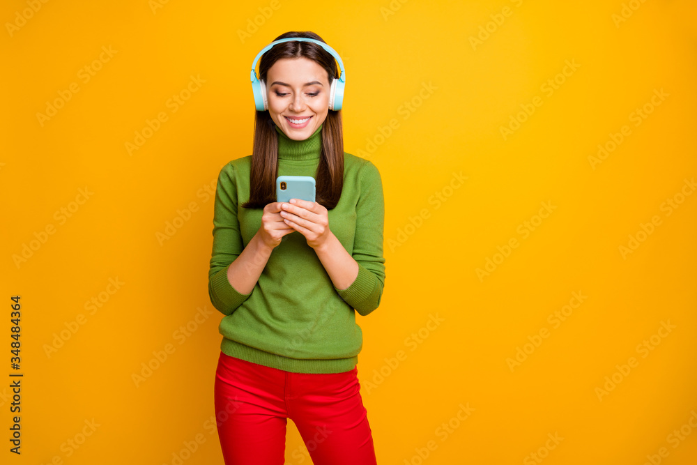 Portrait of positive cheerful girl have weekends use smartphone listen music blue wireless headset choose stereo radio playlist wear stylish clothes isolated shine color background Portrait of positive cheerful girl have weekends use smartphone listen music blue wireless headset choose stereo radio playlist wear stylish clothes isolated shine color background