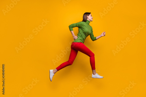 Full length photo of cheerful content girl jump run after black friday sales wear casual style clothing isolated over vivid color background © deagreez