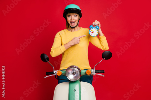 Look my best high score. Energetic crazy girl biker driver ride moped point index finger watch show sporty racing result scream wear yellow pullover isolated bright shine color background