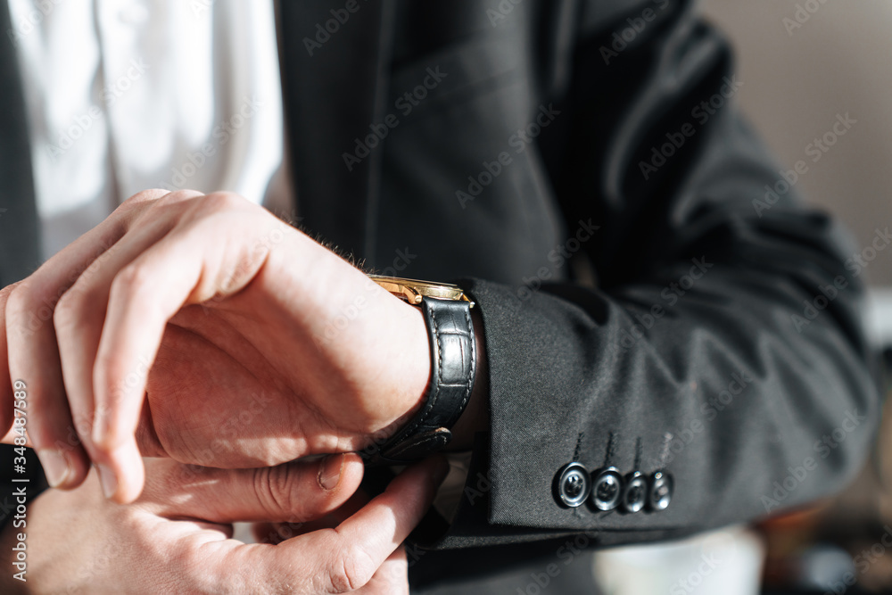 Cropped photo of businessman wearing wristwatch and black suit