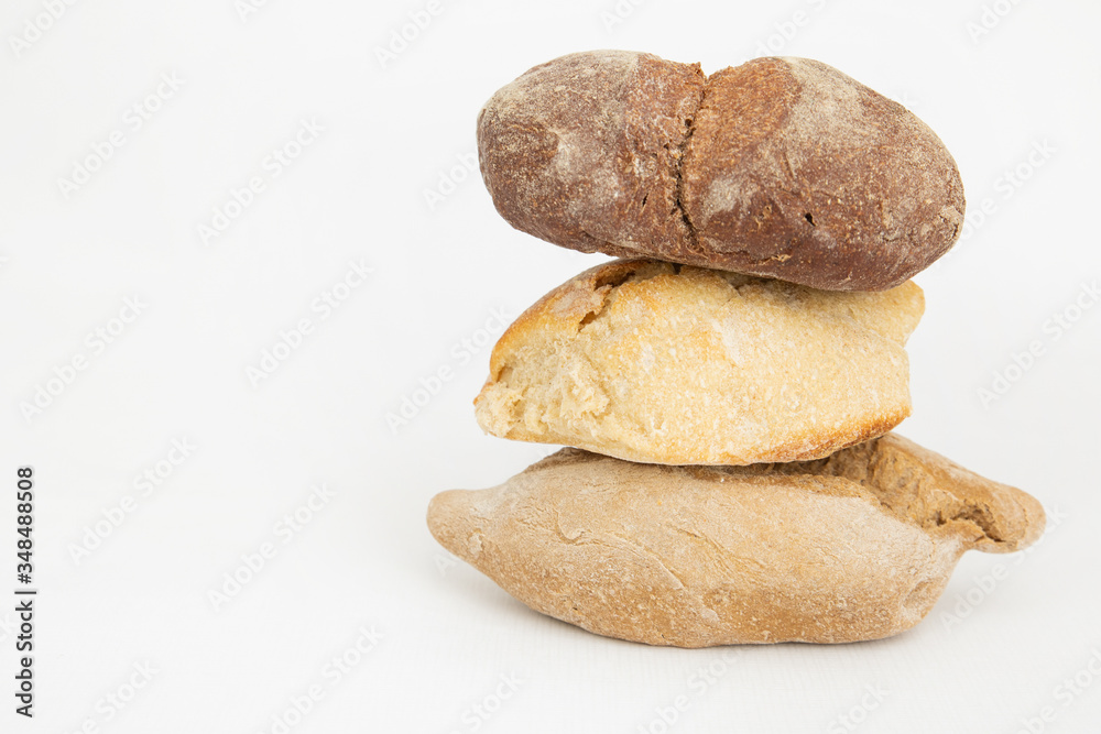 Pile of three wheat and rye breads on left side. Fresh crusty baked loafs and pastry isolated on white background. Studio shot. Side view. Homemade food and baking at home concept Pile of three wheat and rye breads on left side. Fresh crusty baked loafs and pastry isolated on white background. Studio shot. Side view. Homemade food and baking at home concept