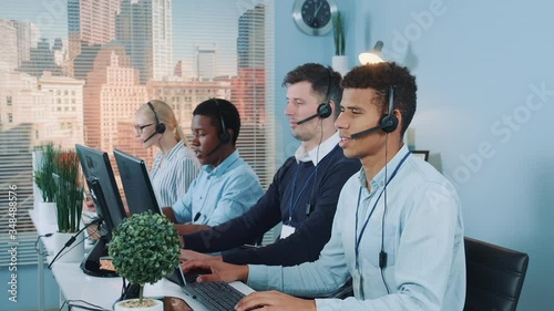 Diverse team of call center customers looking to the camera and smiling after talking to the international clients on phones