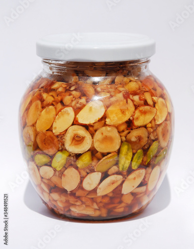 A jar of Greek honey and nuts (pistachios, peanuts, hazelnuts, pine nuts, almonds, walnuts) in natural light
