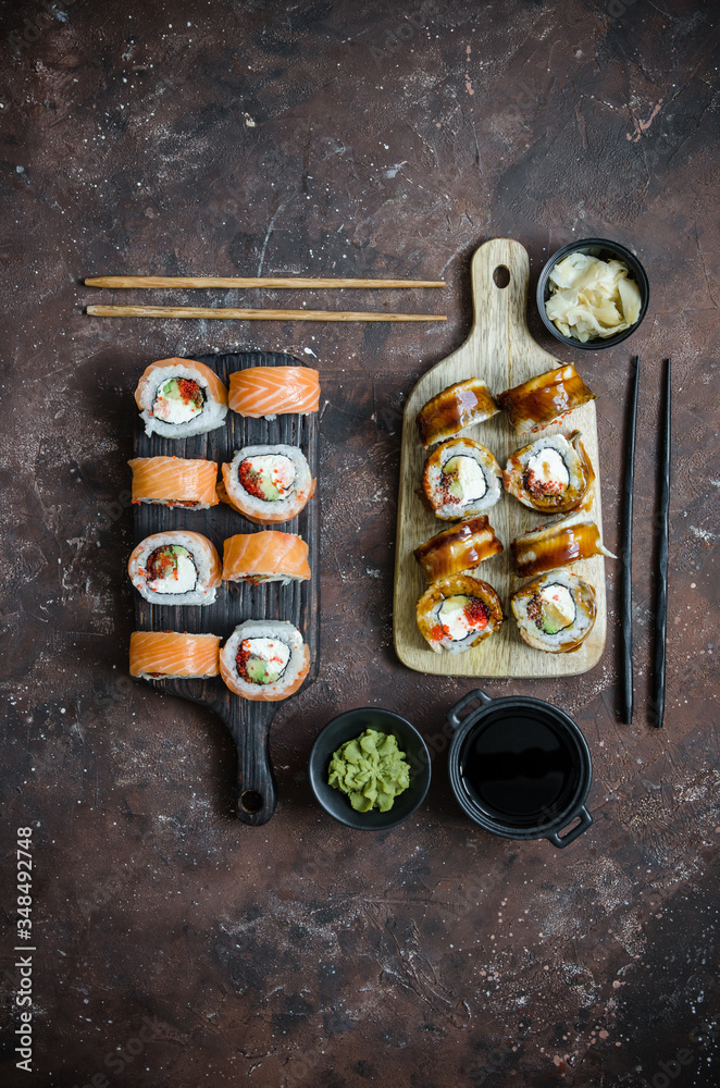 Different Sushi rolls with red fish and eel, wasabi and ginger on a plate on wooden background. Different Sushi rolls with red fish and eel, wasabi and ginger on a plate on wooden background.