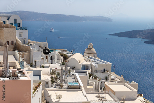 Typical Greek village with church tower lying far over the ocean with cruise ship approaching  Fira  Santorini  Greece