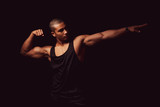 Attraktiver muskulöser junger Mann posiert mit angespannten Muskeln, Portrait vor schwarzem Hintergrund mit copy space 