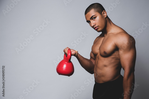 Junger muskulöser Mann trainiert mit einer Kugelhantel, Training mit einer Kettlebell  photo