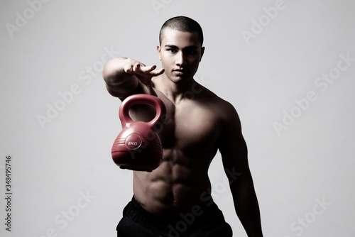 Junger muskulöser Mann trainiert mit einer Kugelhantel, Training mit einer Kettlebell 