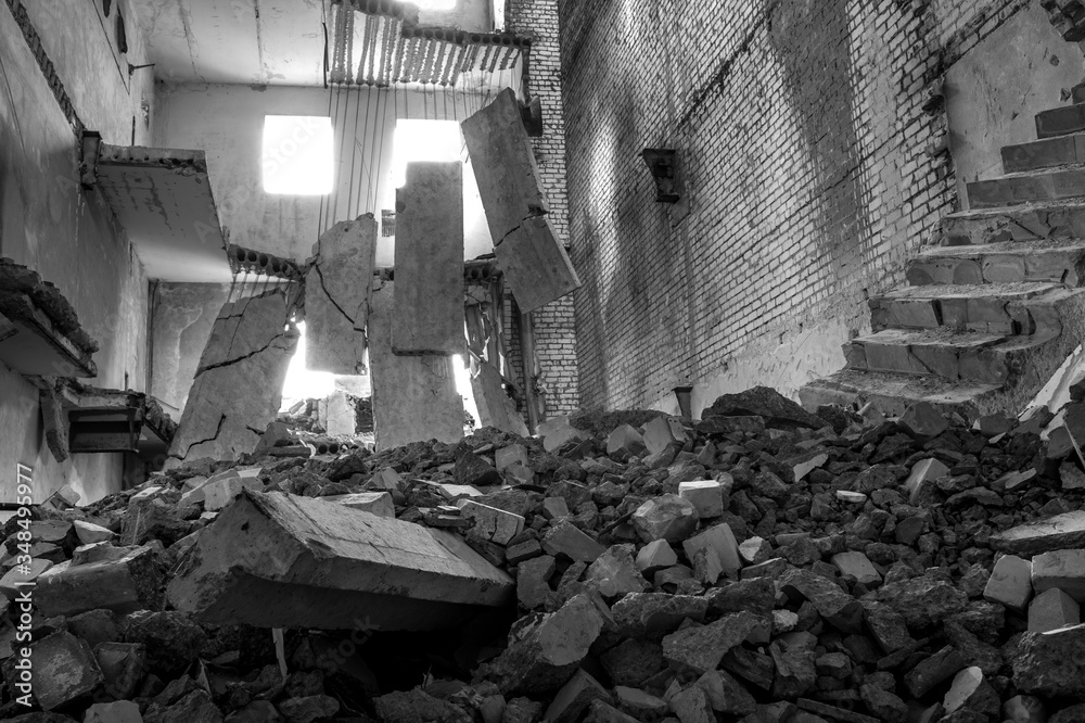 Destroyed concrete building inside with a pile of construction debris in the foreground. Background.