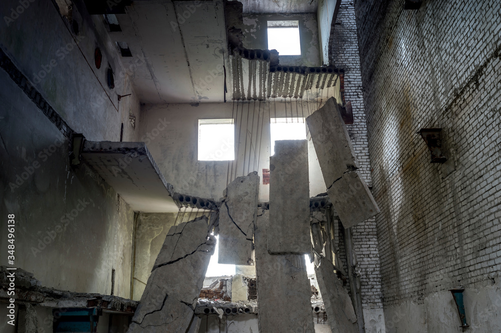 Destroyed concrete building inside with a pile of construction debris in the foreground. Background. Destroyed concrete building inside with a pile of construction debris in the foreground. Background.