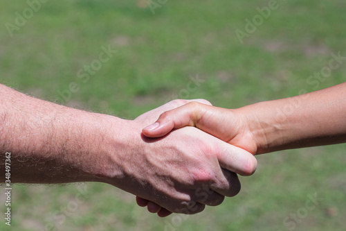 Close-up shot of man shaking hands with woman in the garden. Concept of teamwork. © meeboonstudio