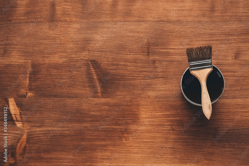 Open can of paint with brown brush on it on wooden background. Repairing concept. Top view. Copy, empty space for text Open can of paint with brown brush on it on wooden background. Repairing concept. Top view. Copy, empty space for text