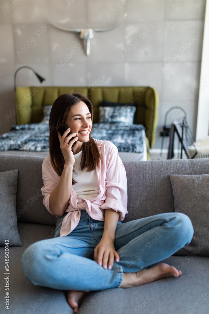 Young woman using mobile phone while sitting on couch at home Young woman using mobile phone while sitting on couch at home