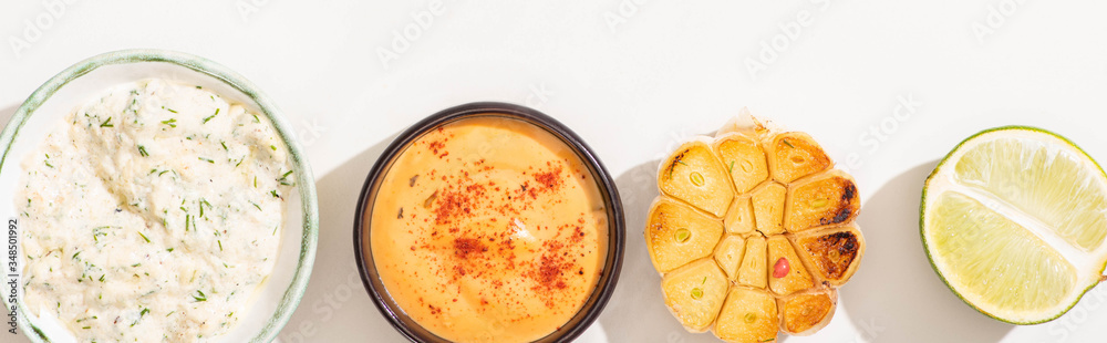 top view of garlic, lime and sauces on white background, panoramic shot top view of garlic, lime and sauces on white background, panoramic shot