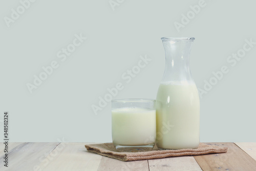A bottle of rustic milk and glass of milk on a wooden table