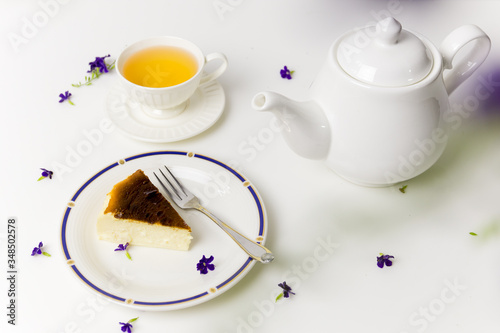 Delicious slice of Basque Burnt Cheesecake with tea cap and teapot at teatime.