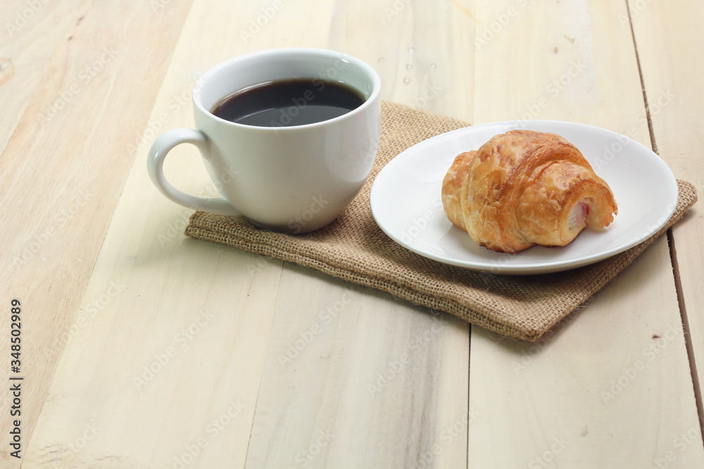 Croissant and coffee isolated on wood table Croissant and coffee isolated on wood table