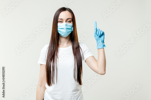 woman showing one finger wearing mask and gloves  isolated on white background © Anastasia