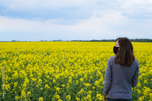 portrait of a girl in a black mask on a background of yellow flowers.outdoors 